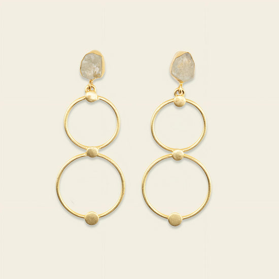 Gold hoop earrings with stone accents on a beige background