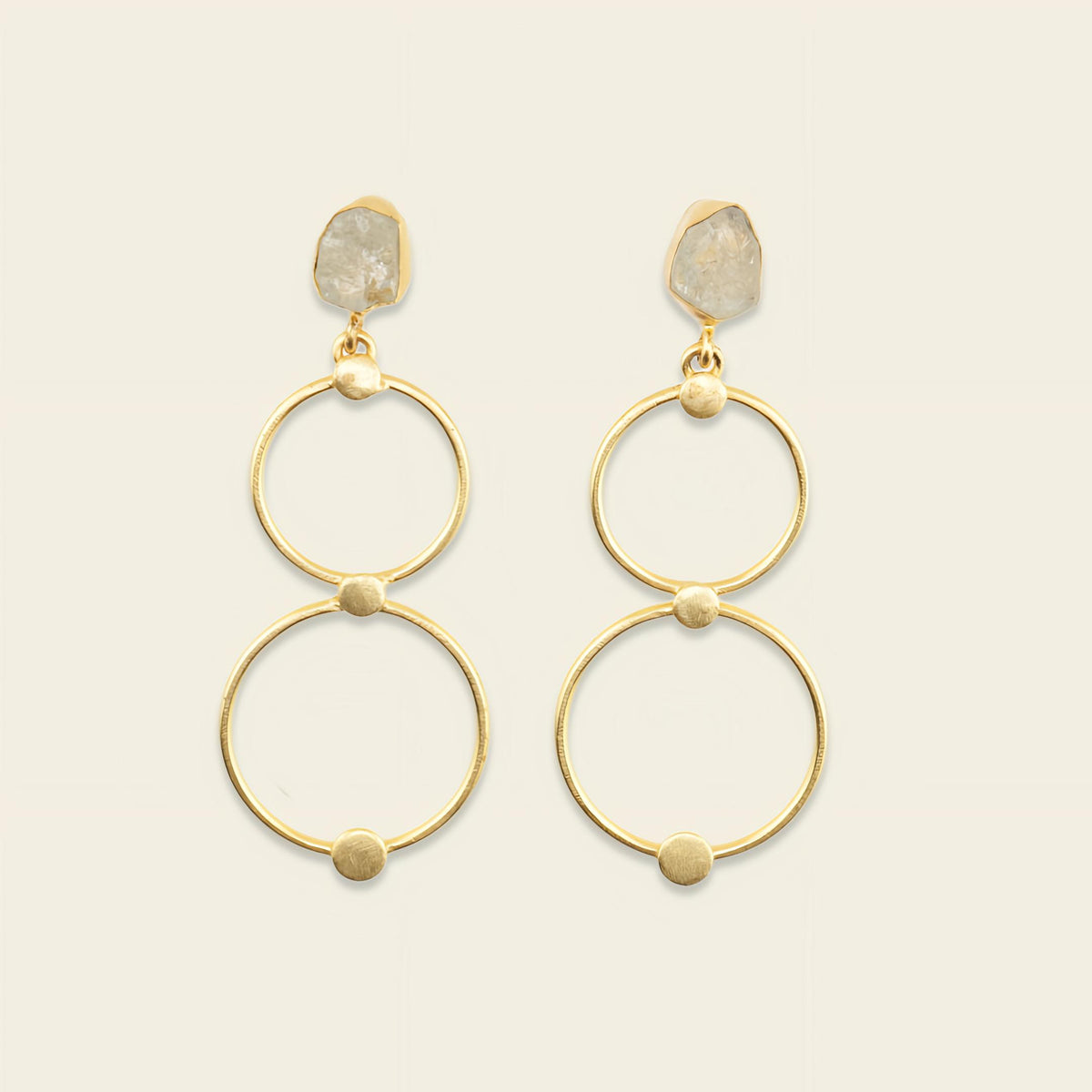 Gold hoop earrings with stone accents on a beige background