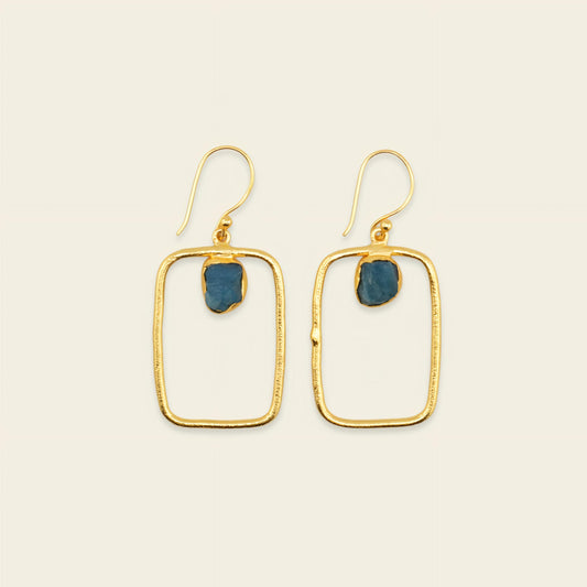 Gold hoop earrings with blue stones on a beige background