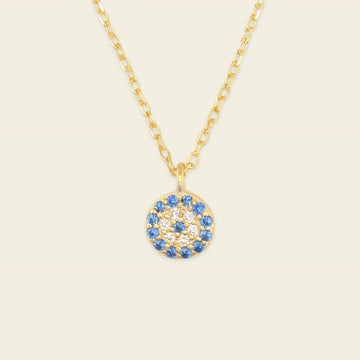 Gold necklace with a blue and white gemstone pendant on a beige background