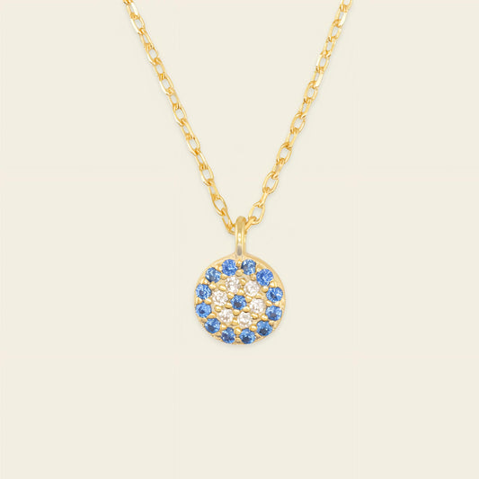 Gold necklace with a blue and white gemstone pendant on a beige background