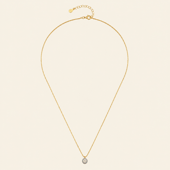 Gold necklace with a single pendant on a beige background