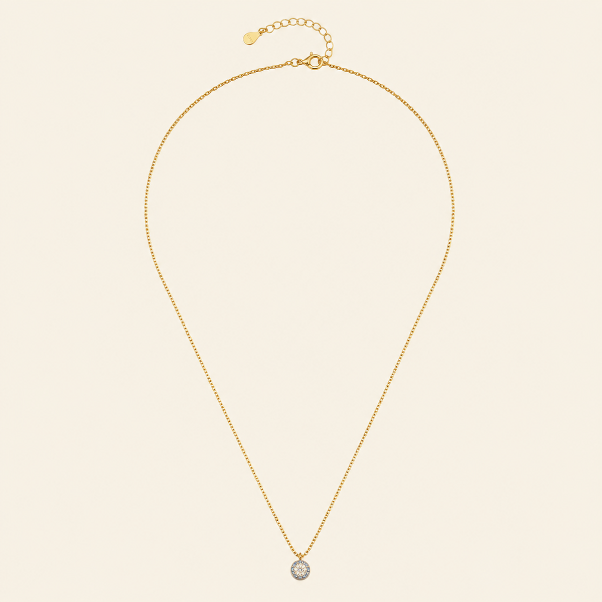 Gold necklace with a single pendant on a beige background