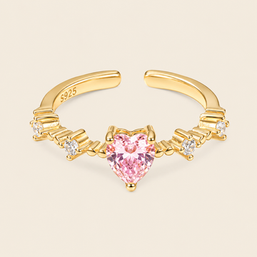 Gold nose ring with a pink heart-shaped gemstone on a beige background