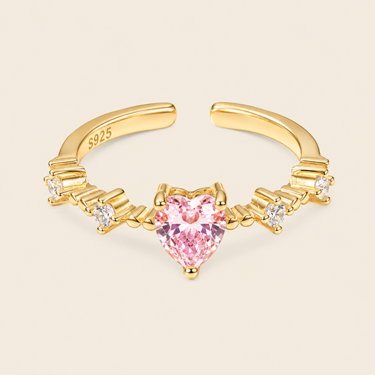 Gold nose ring with a pink heart-shaped gemstone on a beige background