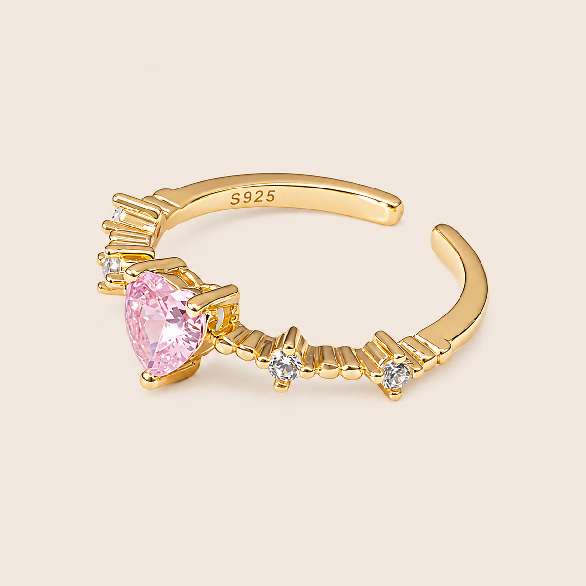 Gold ring with a pink gemstone and small diamonds on a beige background