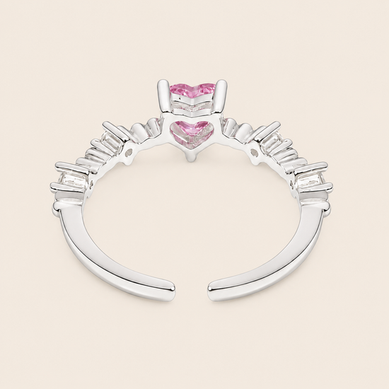 Silver ring with pink heart-shaped gemstones on a beige background