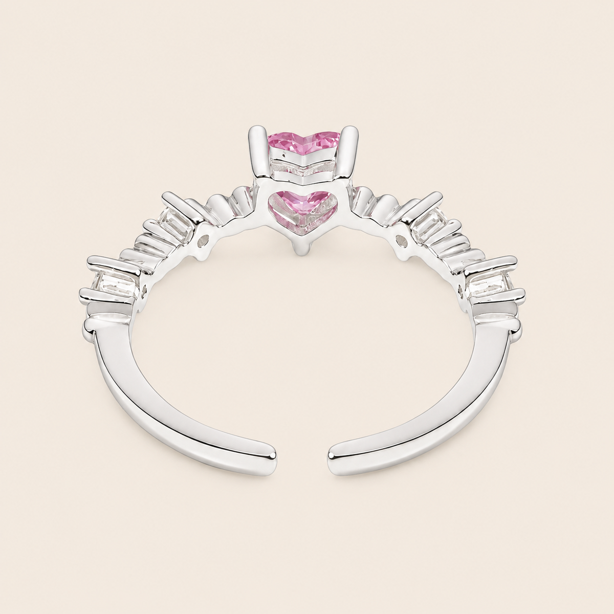 Silver ring with pink heart-shaped gemstones on a beige background