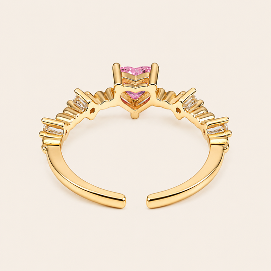 Gold ring with pink gemstones on a beige background