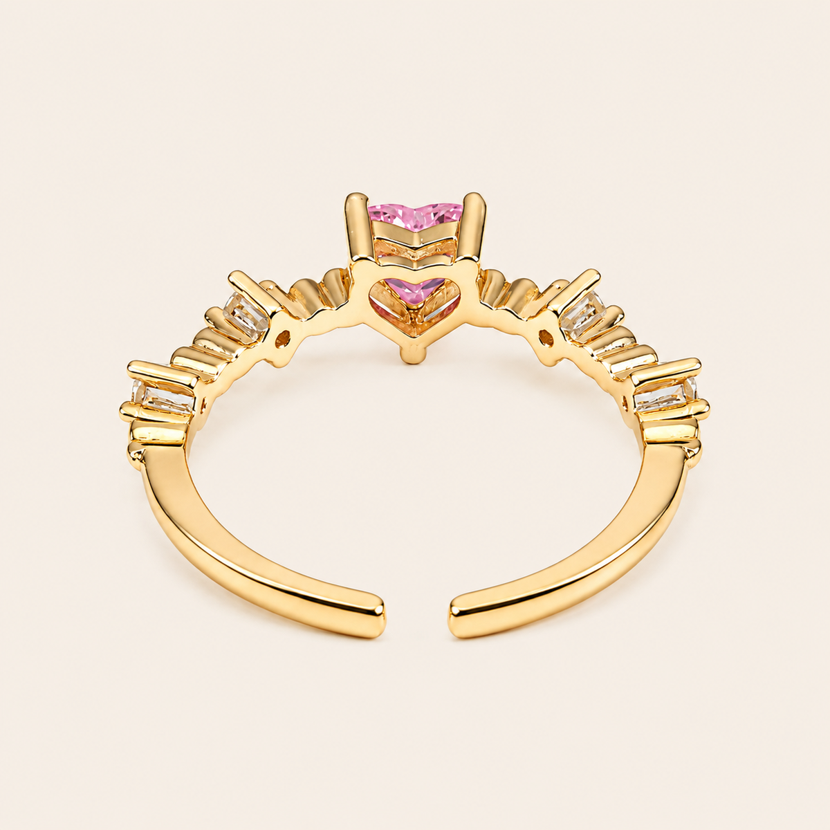 Gold ring with pink gemstones on a beige background