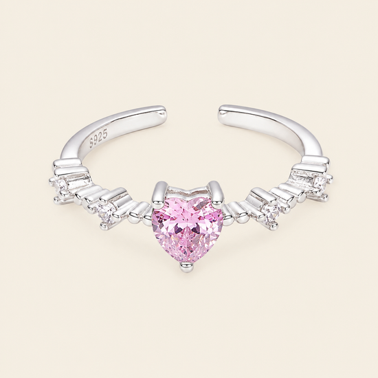 Silver nose ring with a heart-shaped pink gemstone on a beige background