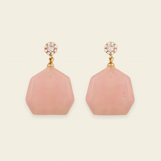 Pink earrings with gold accents on a beige background