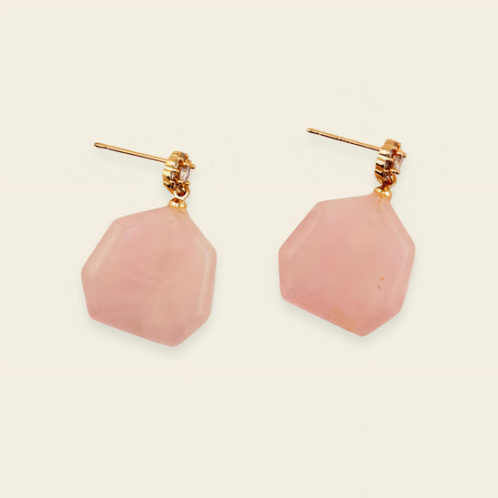 Pair of pink earrings with gold posts on a beige background