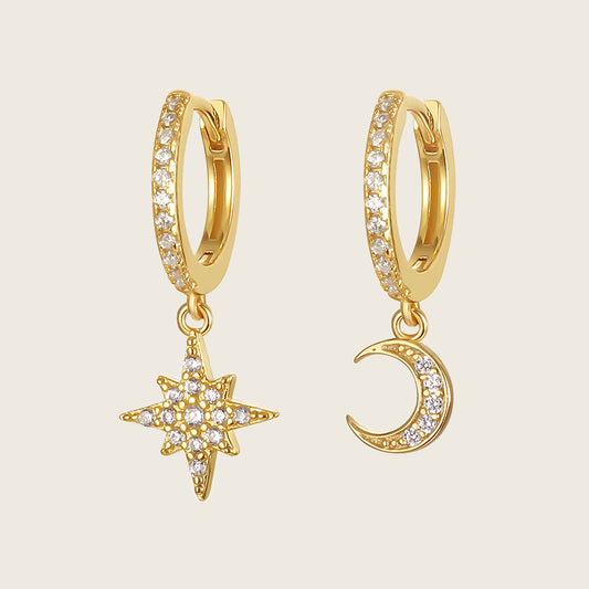 Gold hoop earrings with star and moon charms on a beige background