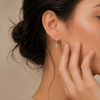 Close-up of a woman wearing a silver earring with a moon design.