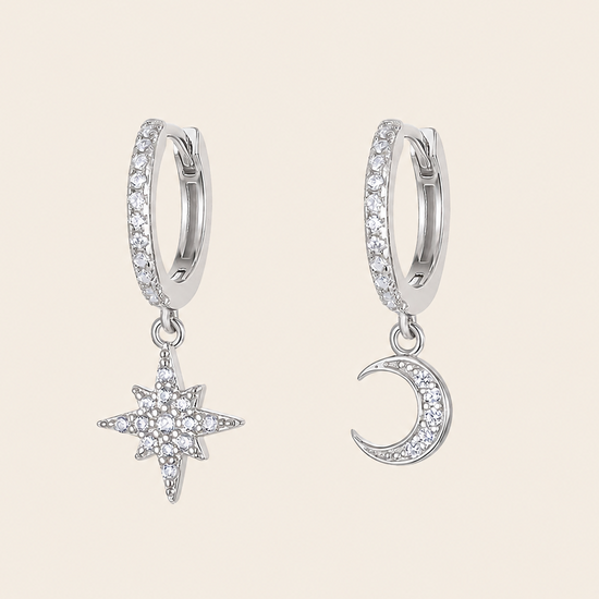 Silver hoop earrings with star and moon charms on a beige background