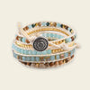 Stack of multicolored beaded bracelets with a central button-like charm on a light background