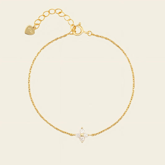 Gold bracelet with a heart charm on a beige background