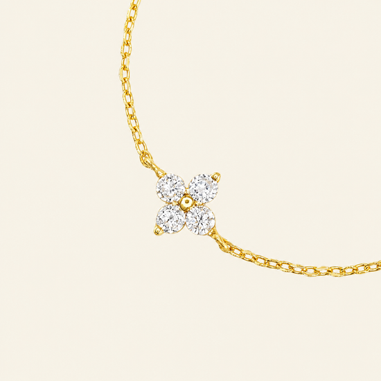 Gold necklace with a diamond pendant on a beige background
