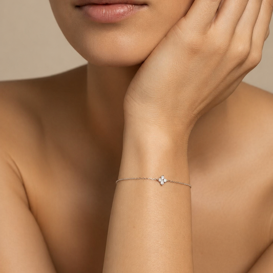 Close-up of a woman's arm wearing a delicate bracelet with a small diamond on a neutral background