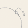 Close-up of a silver chain necklace with a lobster clasp and an adjustable oval link extender, shown on a light cream background.