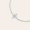 A delicate silver-toned chain bracelet featuring a small four-petal flower pendant set with clear stones, shown against a solid light beige background.