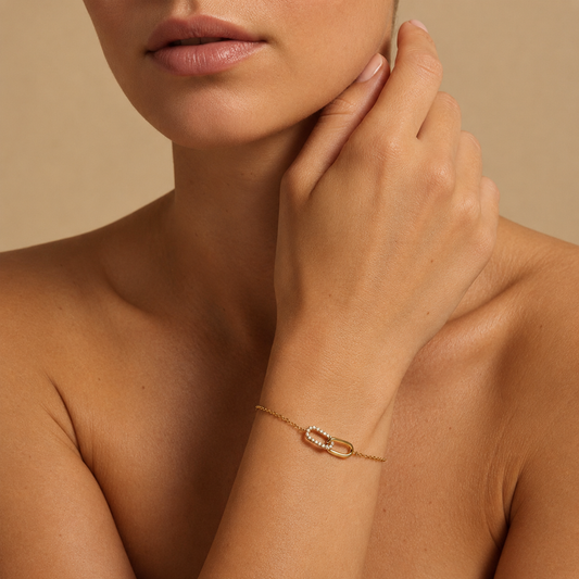 Close-up of a person wearing a gold bracelet on a beige background