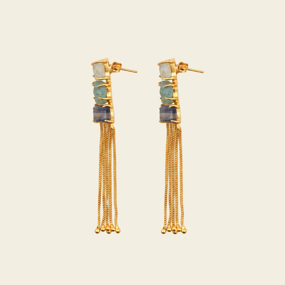 Gold earrings with chain fringes on a light beige background