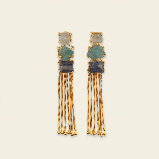 Pair of gold earrings with gemstones on a beige background
