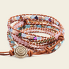 A bohemian-style multi-strand wrap bracelet featuring brown leather cords, colorful faceted beads in pink, blue, green, and purple, and a prominent round gold-toned metal charm with an engraved sun design.