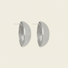 A pair of silver-toned geometric hoop earrings with a smooth outer half and a textured, dimpled inner half, shown on a light cream background.