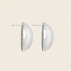 A pair of silver-toned semi-circular hoop earrings with a textured beaded edge and post backs, shown against a solid light beige background.