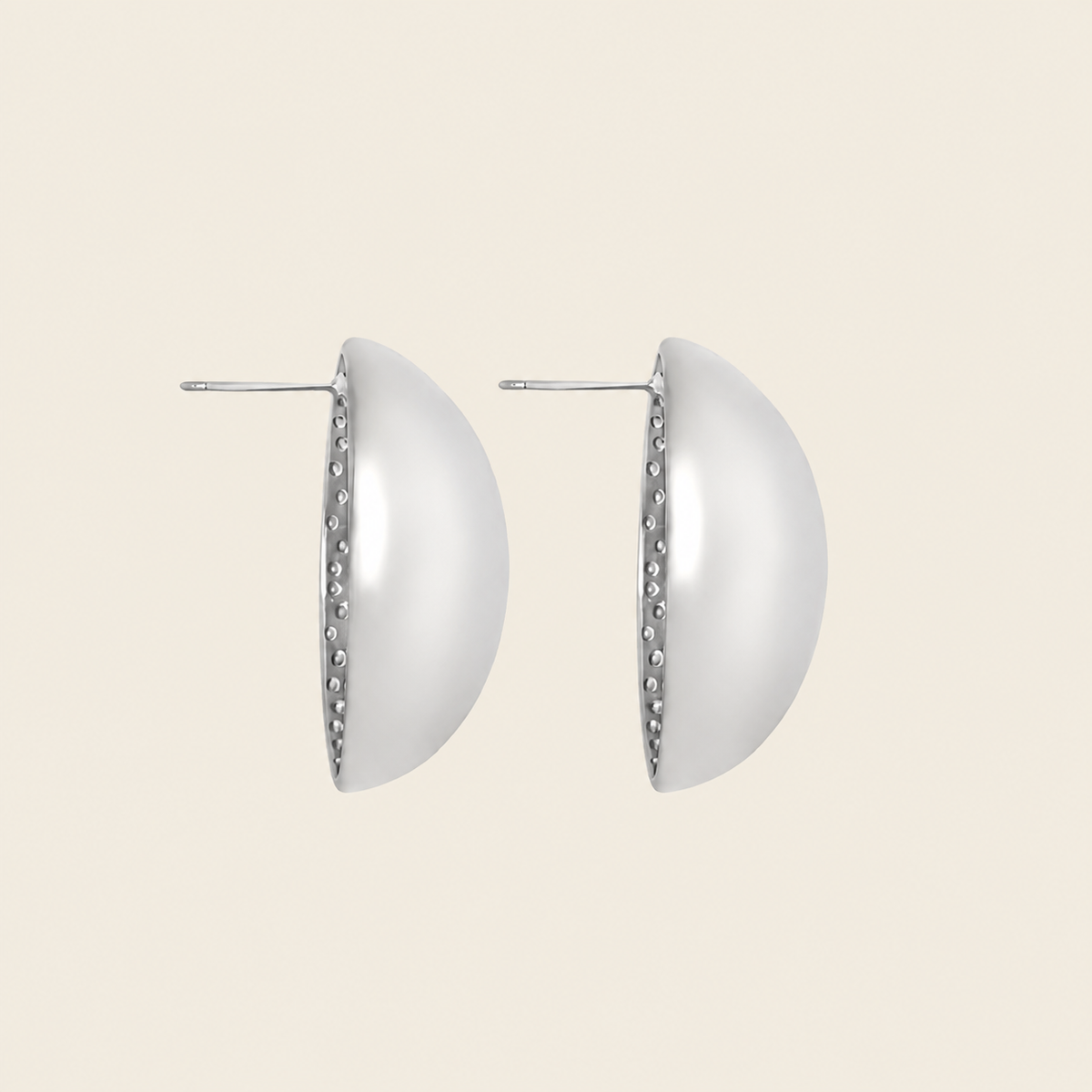 A pair of silver-toned semi-circular hoop earrings with a textured beaded edge and post backs, shown against a solid light beige background.
