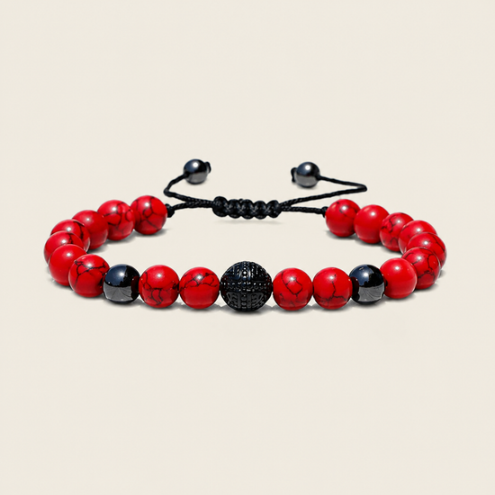 A beaded stretch bracelet featuring red and black marbled beads, a textured black central bead, and a black adjustable cord closure, displayed on a light beige background.
