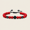 A beaded stretch bracelet featuring red and black marbled beads, a textured black central bead, and a black adjustable cord closure, displayed on a light beige background.