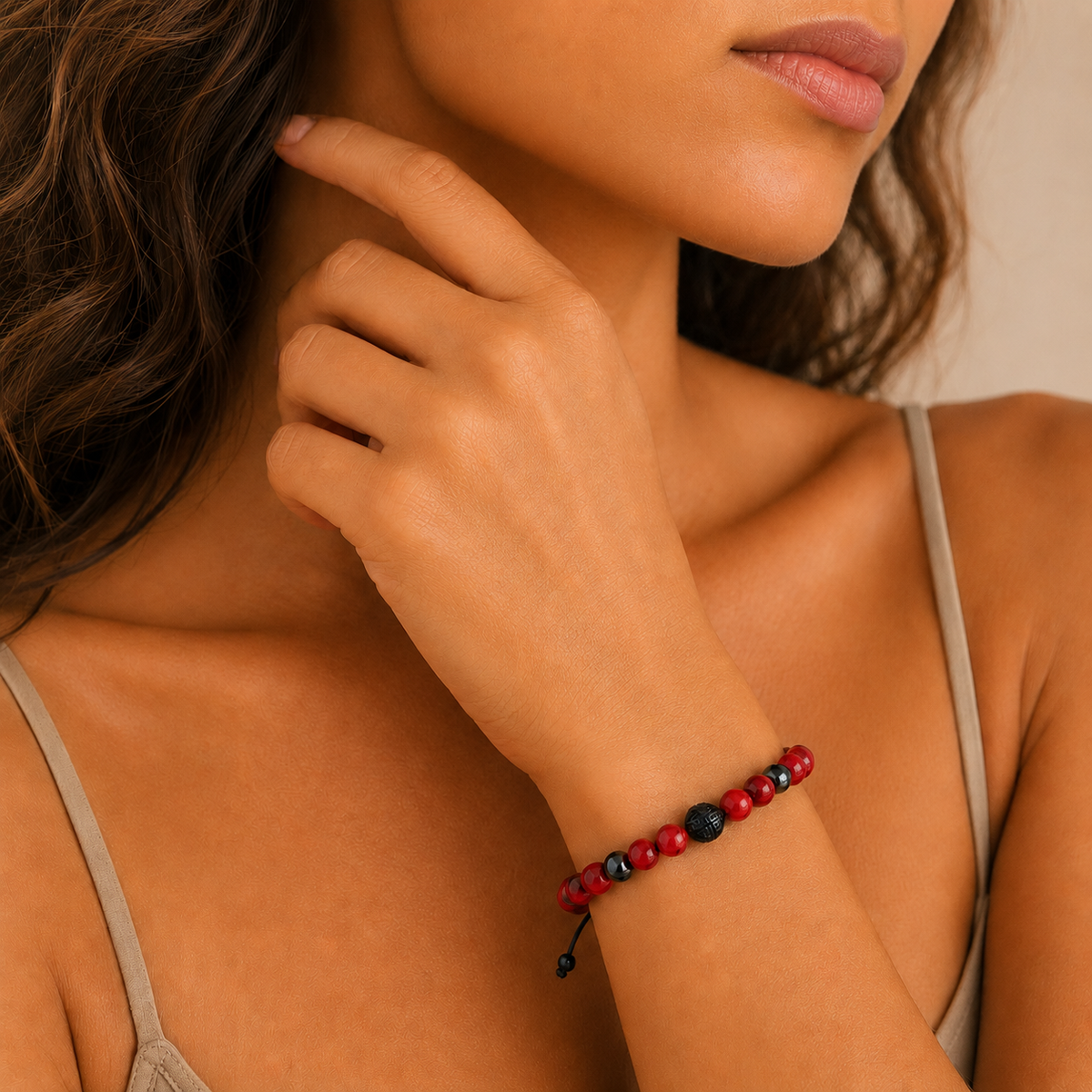 A close-up lifestyle shot of a woman wearing a beaded bracelet on her wrist. The bracelet features alternating red and black round beads with a small black tassel.