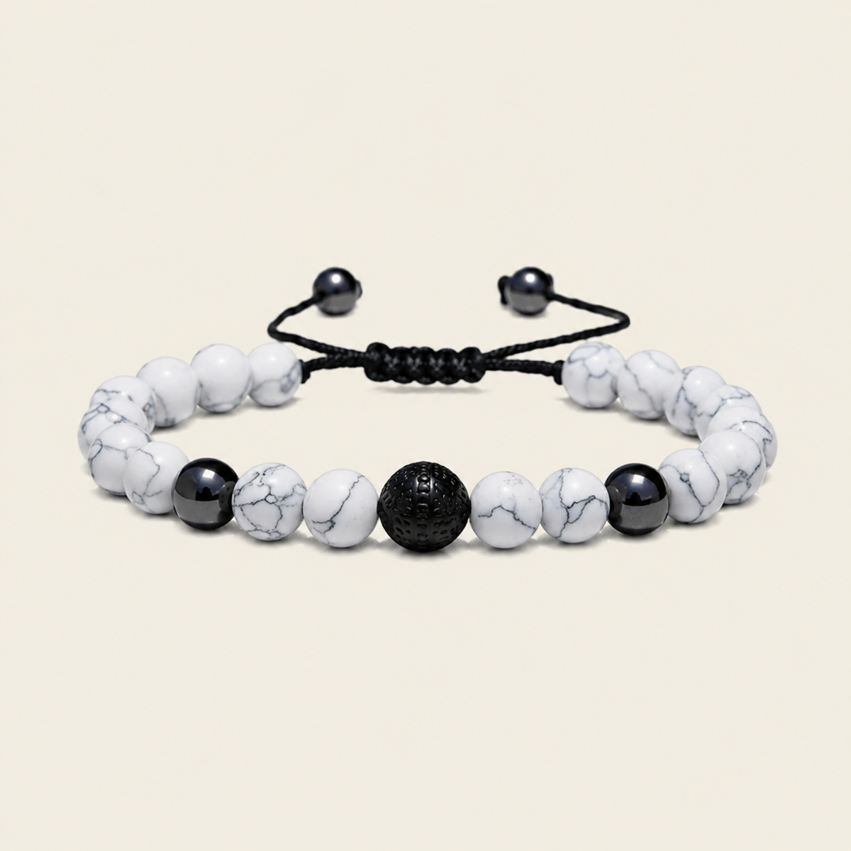 A beaded bracelet with white marble beads, a textured black central bead, and black accent beads on a black adjustable cord, shown on a light beige background.