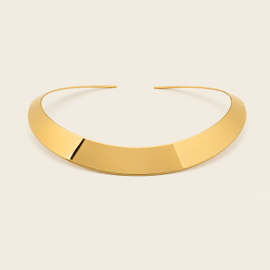 A polished gold-tone open cuff bangle with a smooth, reflective finish, displayed on a light cream background.