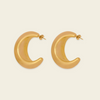 A pair of gold crescent-shaped hoop earrings with a smooth, polished finish, displayed on a light cream background.