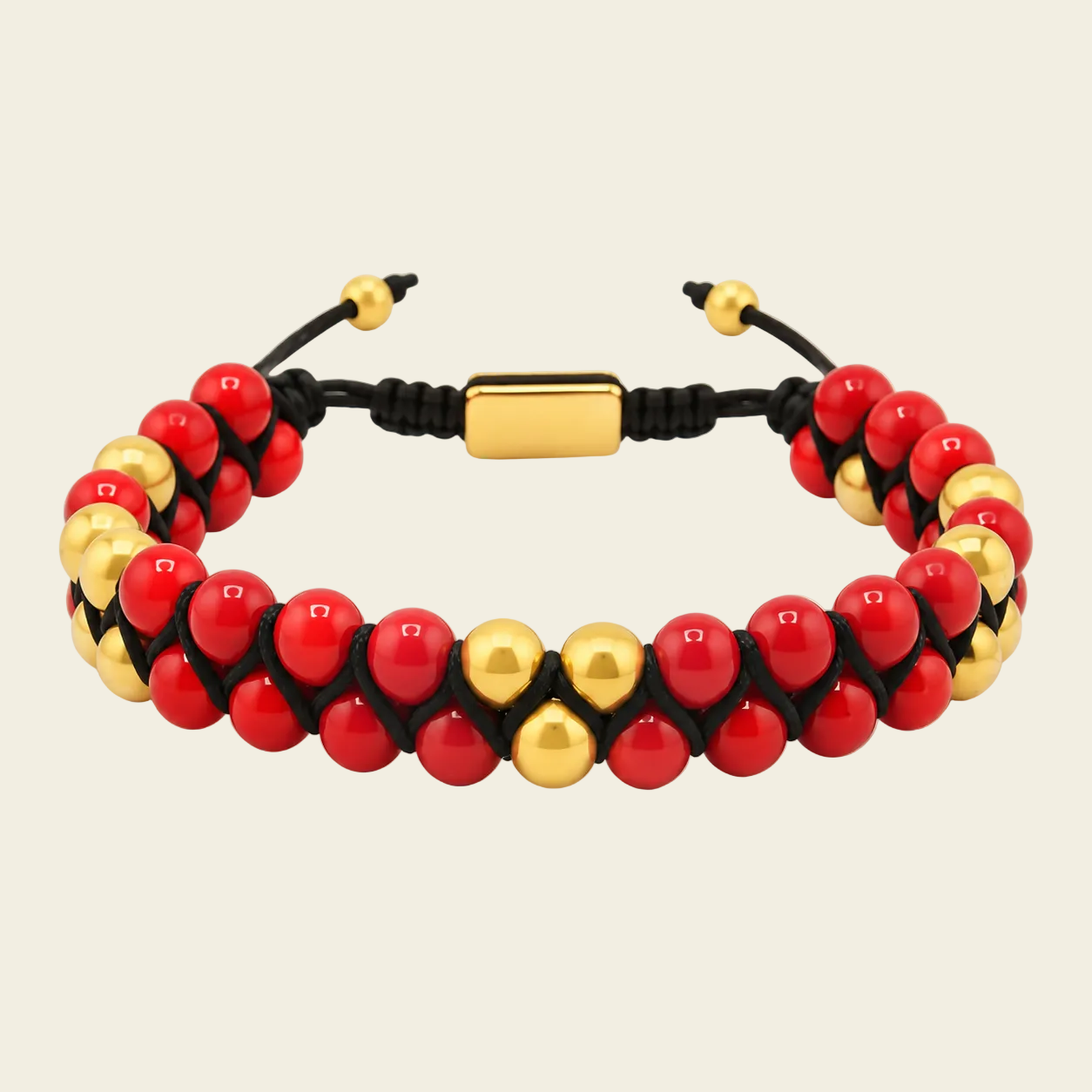 A beaded bracelet featuring glossy red round beads alternating with polished gold metallic beads, strung on a black cord with a rectangular gold clasp, set against a solid light beige background.