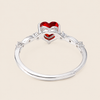 Silver ring with red heart-shaped gemstones on a beige background