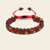 Bracelet with black and brown beads on a red cord against a beige background