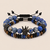 A set of two men's beaded bracelets on a light beige background. The top bracelet features round blue and white marbled beads, black spacer beads, and a central black crown charm.