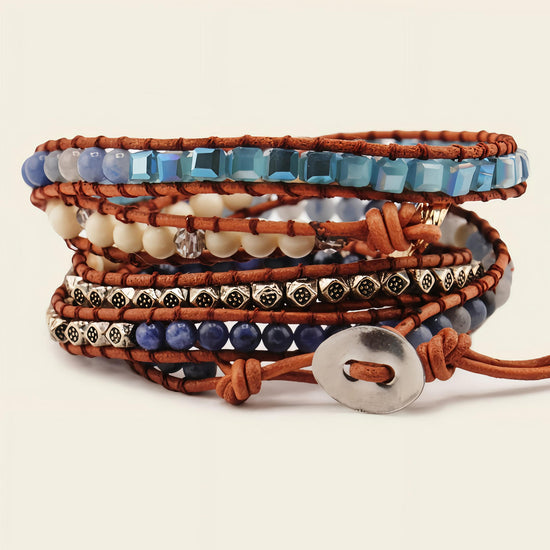 Stack of beaded bracelets with brown leather straps on a beige background