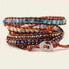 Stack of beaded bracelets with brown leather straps on a beige background