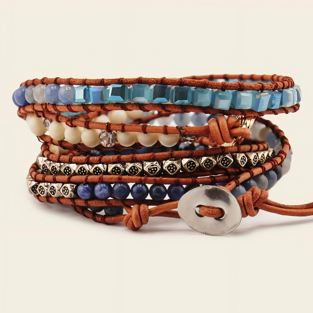 Stack of beaded bracelets with brown leather straps on a beige background