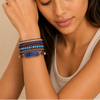 Woman wearing multiple bracelets on her wrist with a neutral background