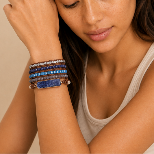 Woman wearing multiple bracelets on her wrist with a neutral background