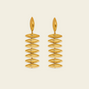 A pair of gold drop earrings with a series of horizontally oriented, polished oval discs hanging from a single elongated teardrop-shaped stud, set against a solid light cream background.