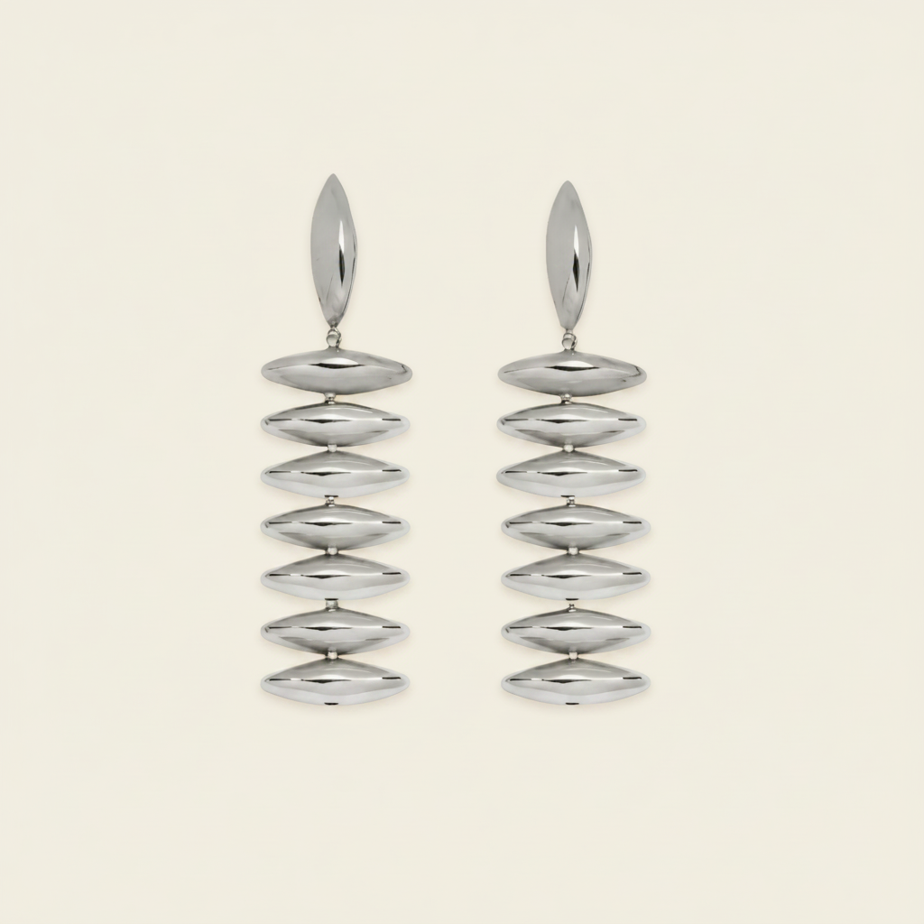 A pair of silver drop earrings with a series of horizontally oriented, polished oval discs hanging from a single elongated teardrop-shaped stud, set against a solid light cream background.